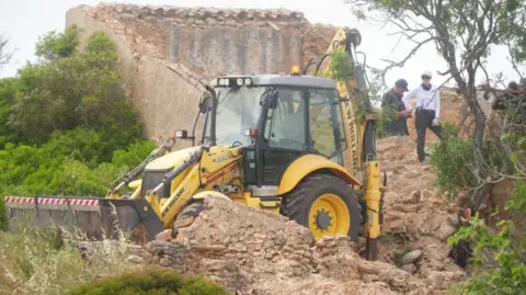 PA Media Search teams use a backhoe digger next to a derelict and abandoned property close to Praia De Luz, Portugal, where searches are being carried out by officers investigating the disappearance of Madeleine McCann, in countryside a few miles from the resort where she was last seen in 2007.