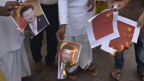 Hindustan Times via Getty Images File picture from 2020 showing men in New Delhi wearing white kurtas, jeans and shirts burning print-outs of Xi Jinping's portrait and the Chinese flag