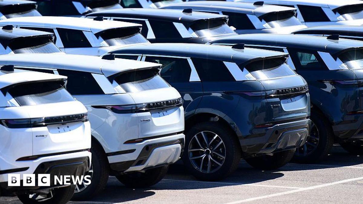 A row of brand new Range Rover cars, some white and some black, standing outside the Jaguar Land Rover factory in Halewood, England