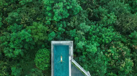 Getty Images Drone aerial shot of woman relaxing in awesome infinity swimming pool in Bali. 
