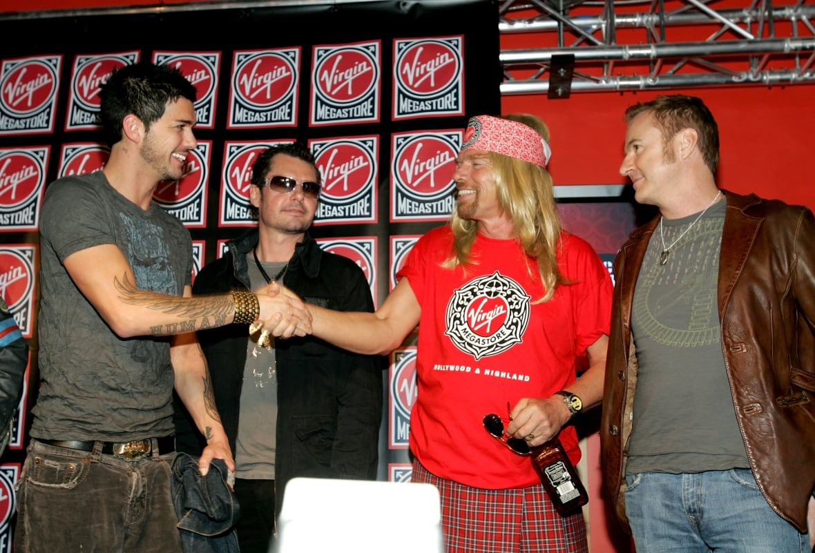 Two men shake on hands onstage, while two others look on.
