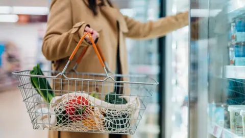Getty Images Shopper holding shopping basket in supermarket 
