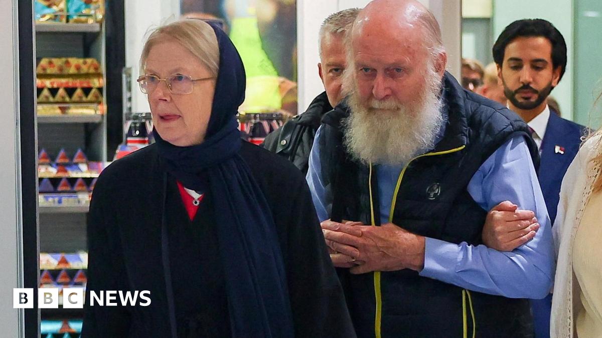 Older British couple Peter and Barbie Reynolds, who were released from Taliban detention in Afghanistan, walking through arrivals at Heathrow Airport. Barbie is wearing deep blue headscarf and dress, a bearded Peter is wearing a blue shirt and dark blue bodywarmer.