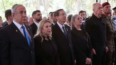 AFP via Getty Images Netanyahu, Herzog and Gallant stand aside several others at a ceremony. The expressions are serious, or sombre, and most people are wearing suits or military attire. 