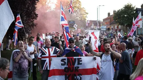 AFP via Getty Images Protesters calling for the closure of the Bell Hotel gather outside the council offices in Epping on 8 August 2025.