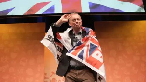 PA Media Former party leader Tim Farron wearing a Blackburn Rovers 'Pride of Lancashire' flag during a rally at the Liberal Democrats autumn conference