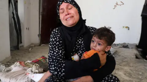 Reuters The grandmother of three-year-old Ibrahim al-Mabhuh, who survived an Israeli air strike on a house in Gaza City that killed his parents and two sisters, holds him (3 September 2025)