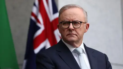 Getty Images Anthony Albanese in a suit standing in front of an Australian flag
