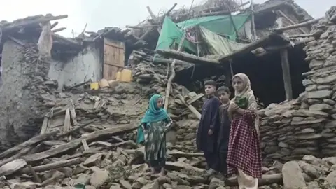 Ariana News Afghanistan A group of children stand in front of the rubble of a building