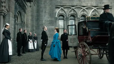 Netflix Michael McElhatton and Ann Skelly outside Penrhyn Castle in House of Guinness with a horse drawn carriage