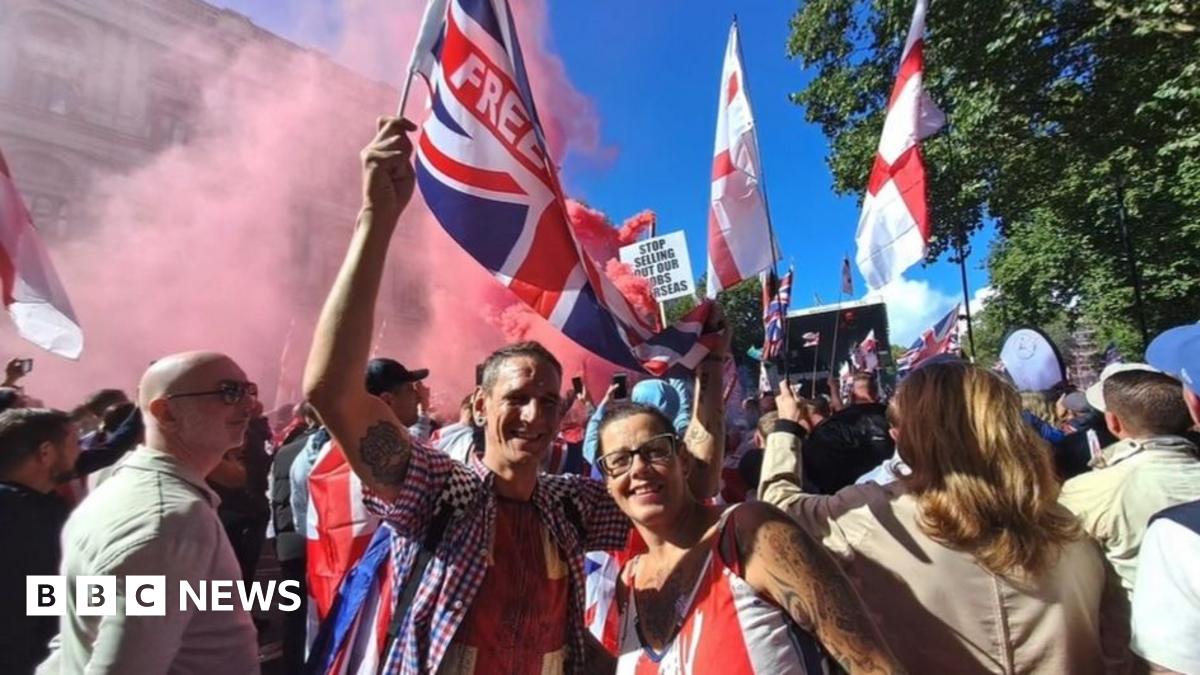 Sam Philpott stands behind the bar with his wife Suzanne. Sam is wearing a checked shirt. Suzanne who is wearing a cream and brown patterned shirt has her arm resting on a Fosters beer tap on the bar