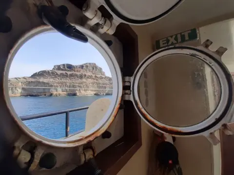 Matthias Berg/Klima Segler The view through a porthole out to the coast of Puerto Mogan in Gran Canaria. The ship was at anchor there after returning to the archipelago in the wake of the rescue operation