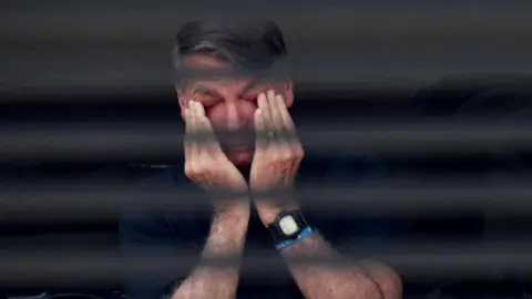 Reuters Jair Bolsonaro wipes his eyes with his hands in a photo captured through the blinds of a window of his home in Brasilia