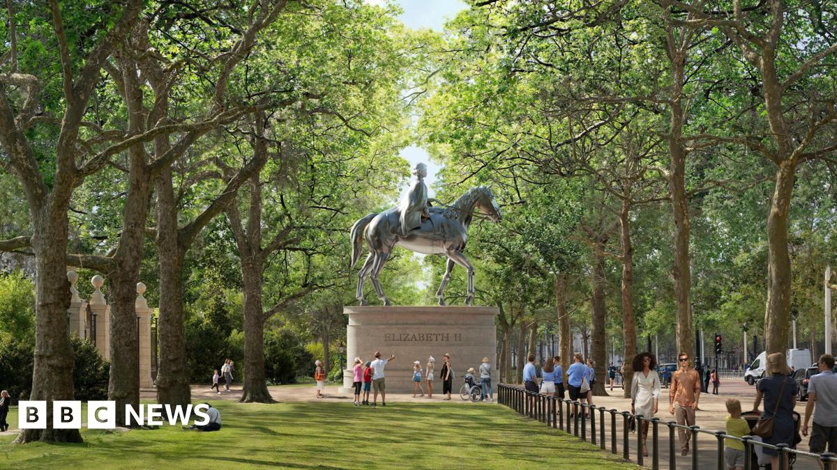 A mock-up of St James's Park with a large statue of Queen Elizabeth II on horseback high above ground. The statue sits on a plinth in between two rows of tall trees. People are milling about around it and on the pavement off to the right. It is daytime.