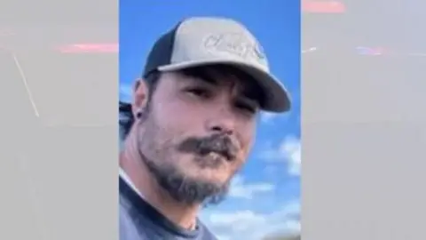 Wenatchee Police Department An image of Travis Decker released by police, where he is wearing a cap, with a blue, cloudy sky in the background