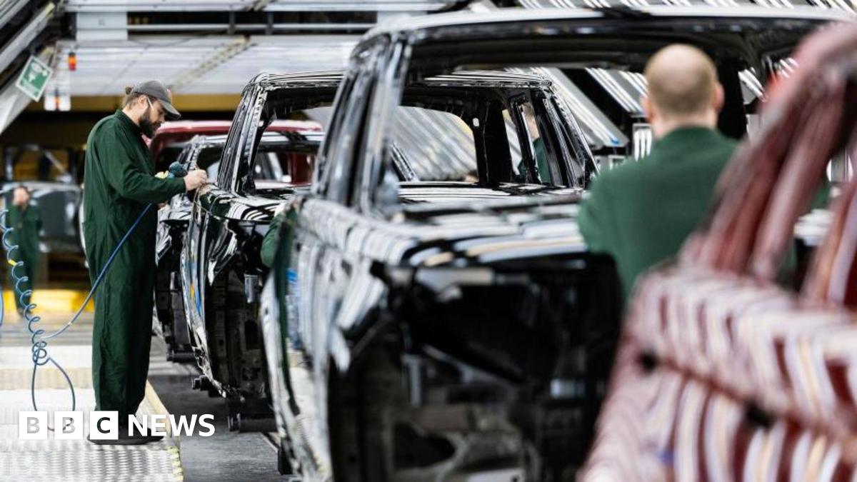 An employee where dark green overalls and a cap polishes paint on the bodywork of a Range Rover sports utility vehicle (SUV) in the paint shop at Jaguar Land Rover vehicle manufacturing plant in Solihull, UK.