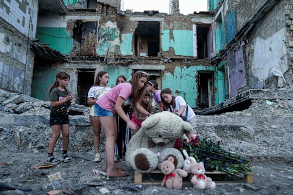 Girls wipe dust off of a teddy bear in front of a house that was destroyed by a Russian strike in Kyiv, Ukraine, last week.