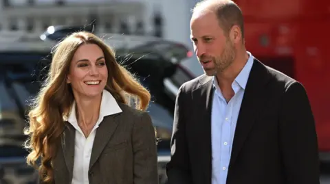 Daily Telegraph/PA Shoulder crop of William and Catherine. William is wearing a black blazer and light blue shirt. Catherine is wearing a tweed-style jacket and white shirt. She has blonde hair. Both are smiling and posing outside the museum.