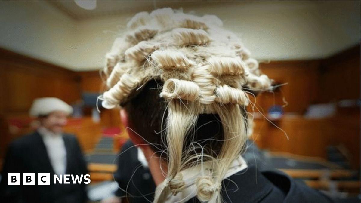 A laywer in a wig, viewed from behind, in a court room