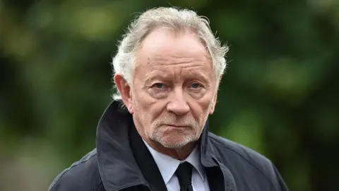 Getty Images Phil Coulter. He has white wavy hair, wearing a black coat, white shirt and black tie.