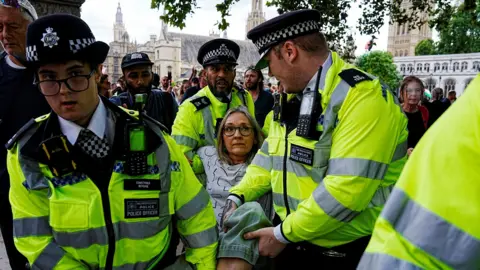 Reuters Several police officers carry a woman away by her limbs