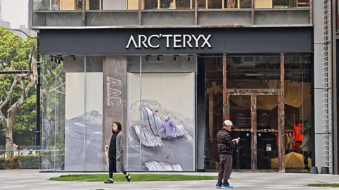 Getty Images Pedestrians walk past a Arc'teryx flagship store in Shanghai, China on March 27, 2025. 