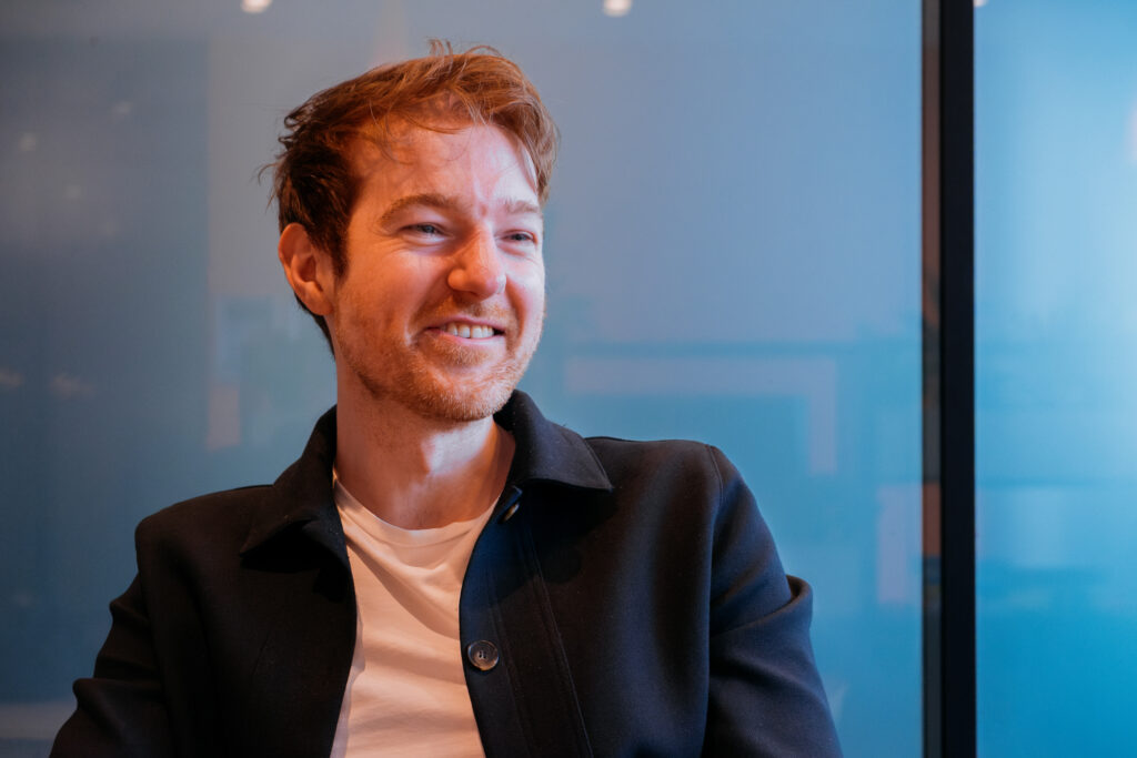 Man with reddish hair and close-cropped beard sitting at a table.