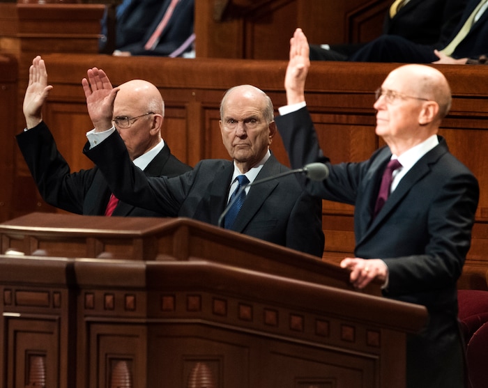 (Rick Egan | The Salt Lake Tribune) Members of the First Presidency raises their hands as they sustain Russell M. Nelson and the First Presidency of the church during a  Solemn Assembly at General Conference in 2018.
