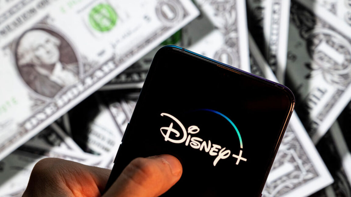Disney+ (plus), logo seen on an Android mobile device screen with the currency of the United States dollar icon, $ icon symbol in the background