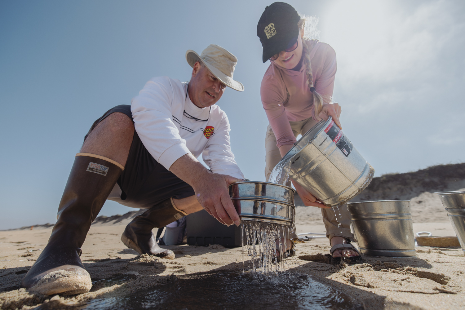 Image of Steve Lonhart and LIbby Mohn filtering sand and ocean water samples to search for microplastics in the ocean.