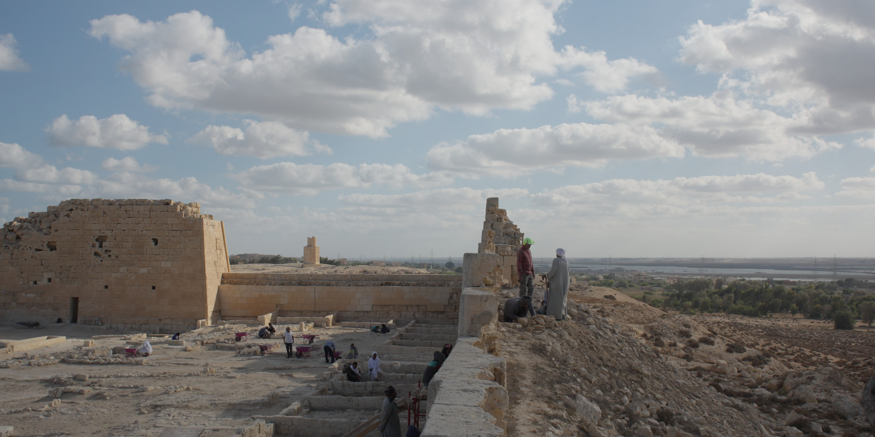An excavation at a temple in Egypt with water in the distance.