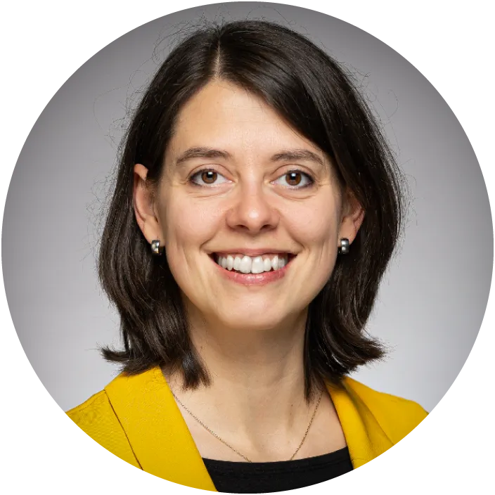A woman in a yellow blazer smiles at the camera.