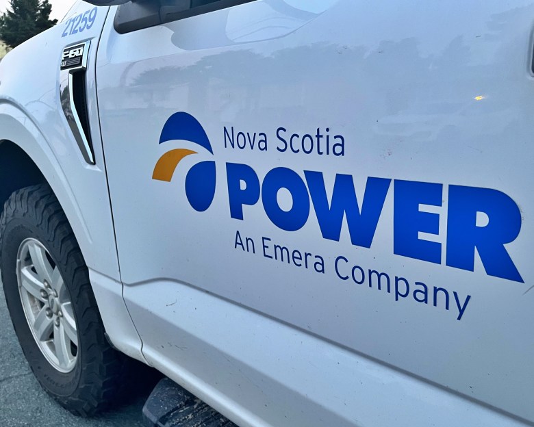 The driver's side of a white work vehicle is seen on the side of a road. On the door are the words "Nova Scotia Power An Emera Company."