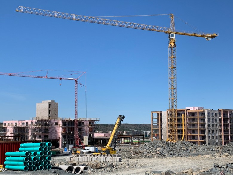 A construction site. Several multi level buildings are going up, and a large crane dominates the photo.