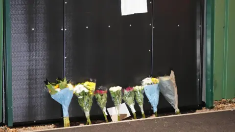 Eddie Mitchell Seven bunches of flowers leaning against a black wall