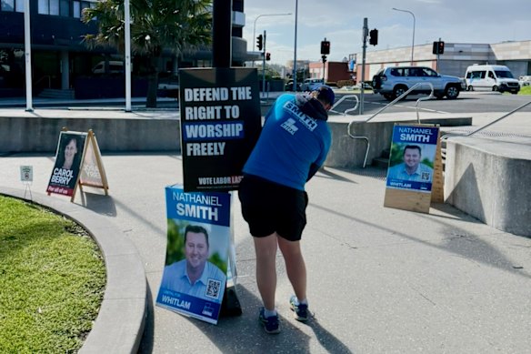 A Brethren member in a Liberal Party T-shirt puts up a poster authorised by Freedom Party candidate Morgan C. Jonas in the NSW seat of Whitlam.