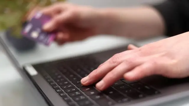 A woman using a laptop as she holds a bank card