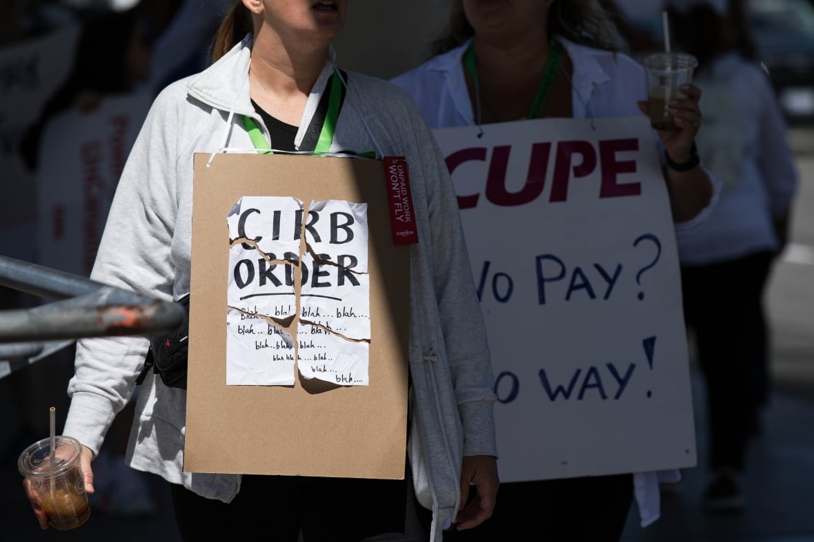 A striking Air Canada flight attendant holds a sign that says "CIRB order - blah, blah, blah."