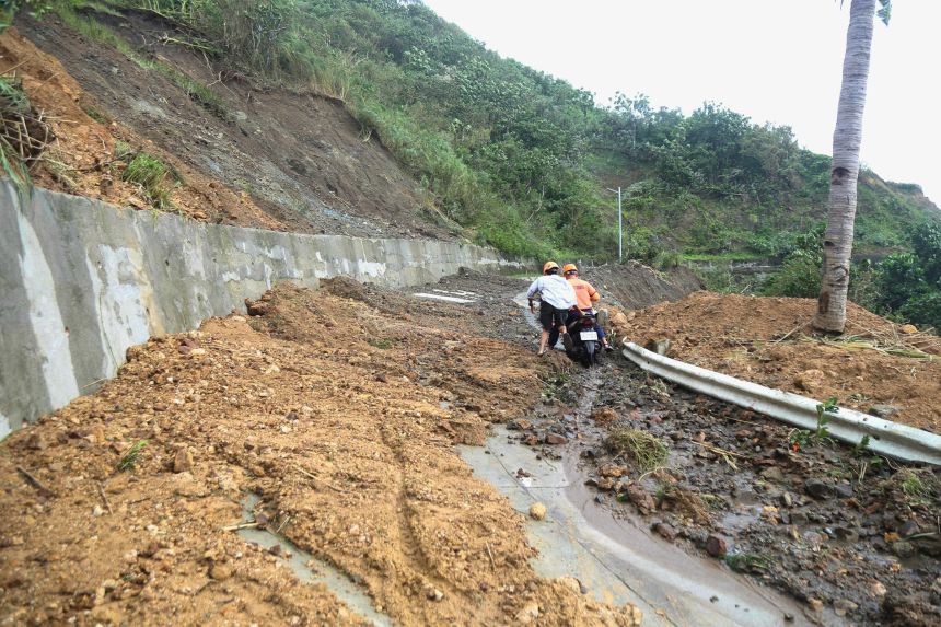 Two men negotiate a landslide after Typhoon Ragasa in Uyugan, Batanes province, northern Philippines on September 23, 2025.
