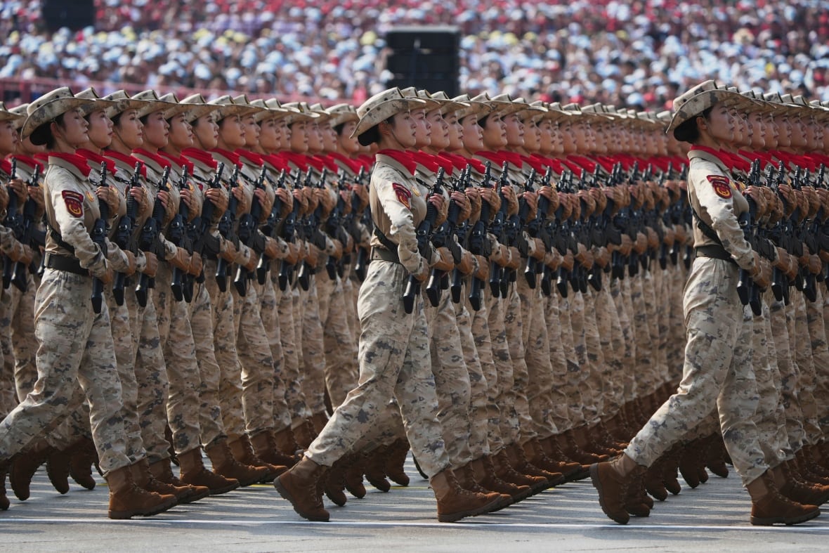 Women holding guns and wearing camouflage walk in extermely geometrical lines. 