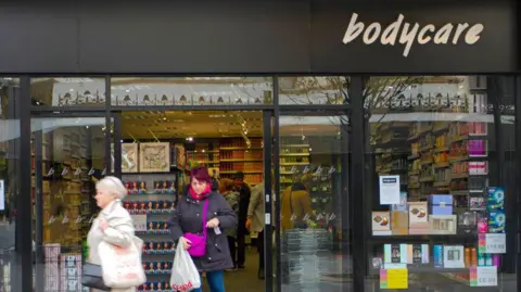 Alamy Two customers leave a Bodycare shop, where shelves and shelves of beauty and cosmetic products reach from the ceiling to the floor.