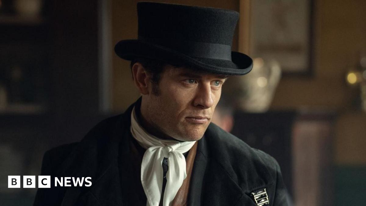 James Norton in character as Sean Rafferty wearing a black top hat and white scarf