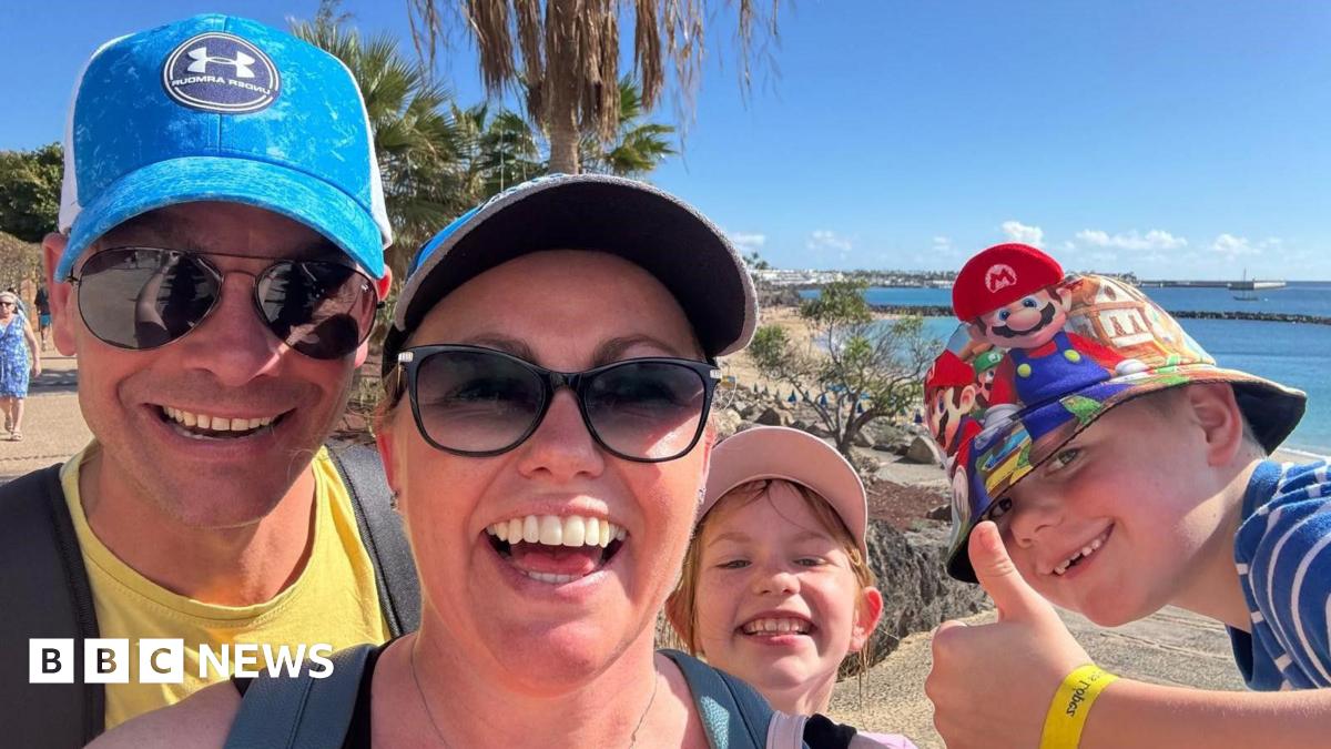 Matt, Gemma and their children smiling at the camera while on holiday together. A beach is behind them.
