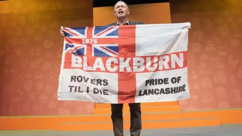 PA Media Former party leader Tim Farron holding a Blackburn Rovers 'Pride of Lancashire' flag during a rally at the Liberal Democrats autumn conference