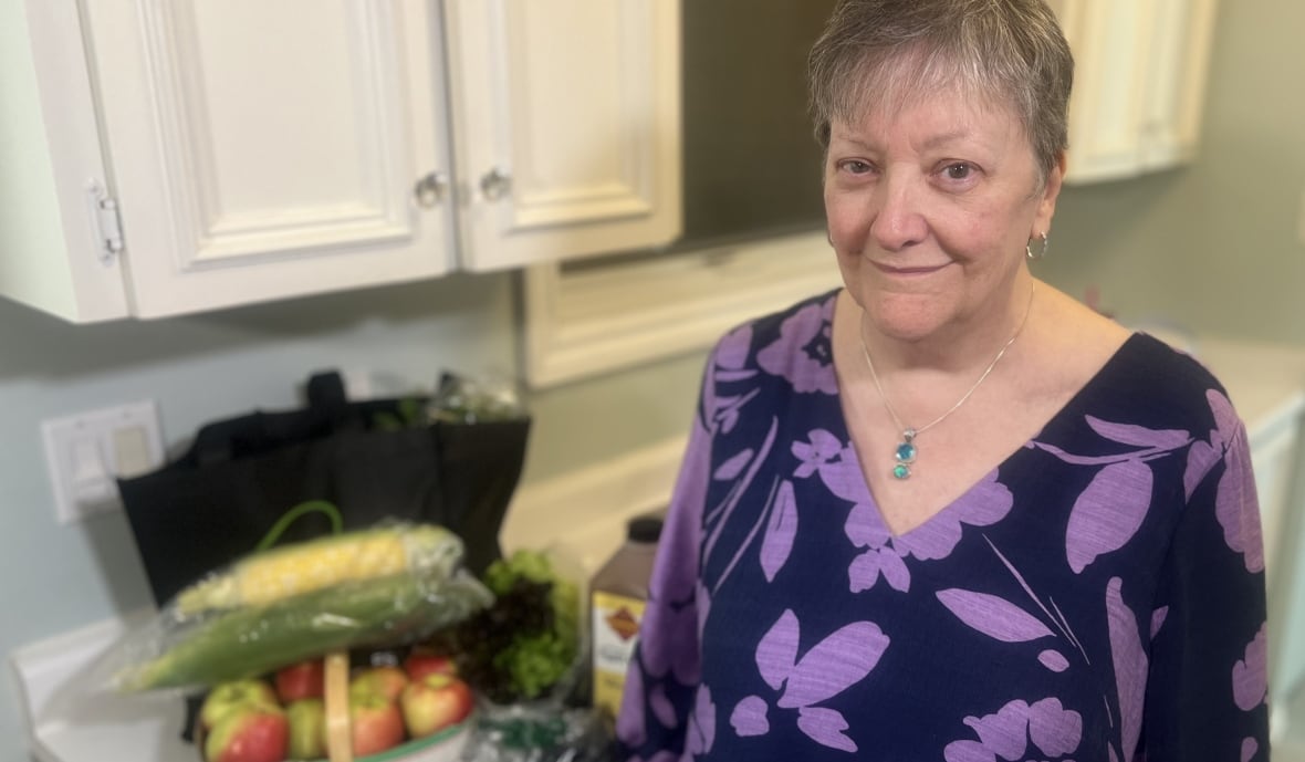 Brenda Nicholls in her home standing next to fruit on her counter. 