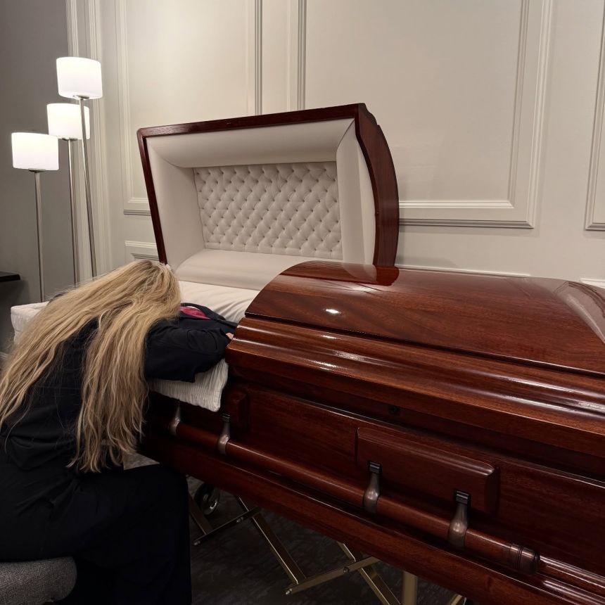A photo from Erika Kirk's instagram shows her kneeling beside her husband's, Charlie Kirk, casket.