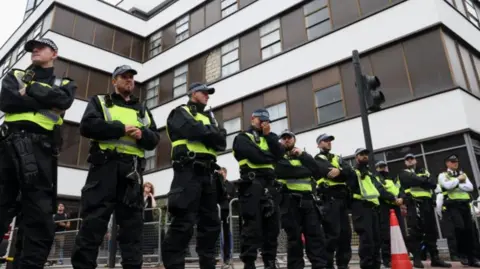 Reuters A row of police lined up on a street outside of a tall building 