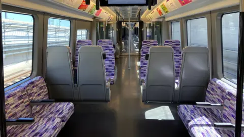 BBC/Harry Low Interior of Elizabeth line train shows empty carriage with purple seats and sun streaming through the windows