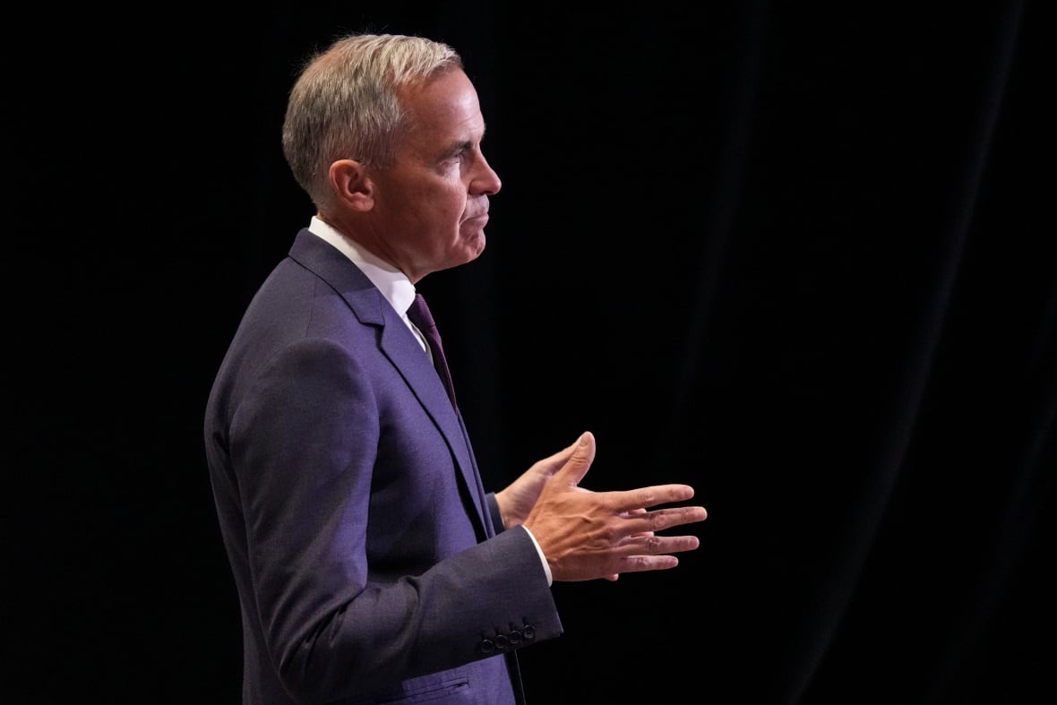A man in a suit gestures with his hands as he speaks to unseen people.