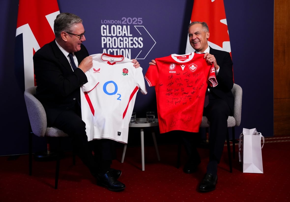 Two men in suits exhcnage signed rugby jerseys